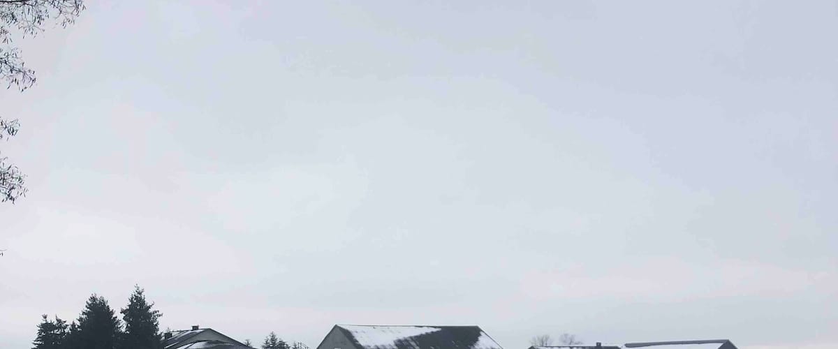 A snow-covered road with buildings in the background.