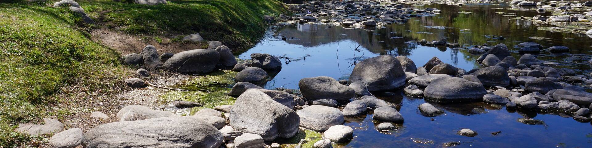 Landscape view of Santa Rosa river going trough Calamuchita small town. Large green trees in both sides