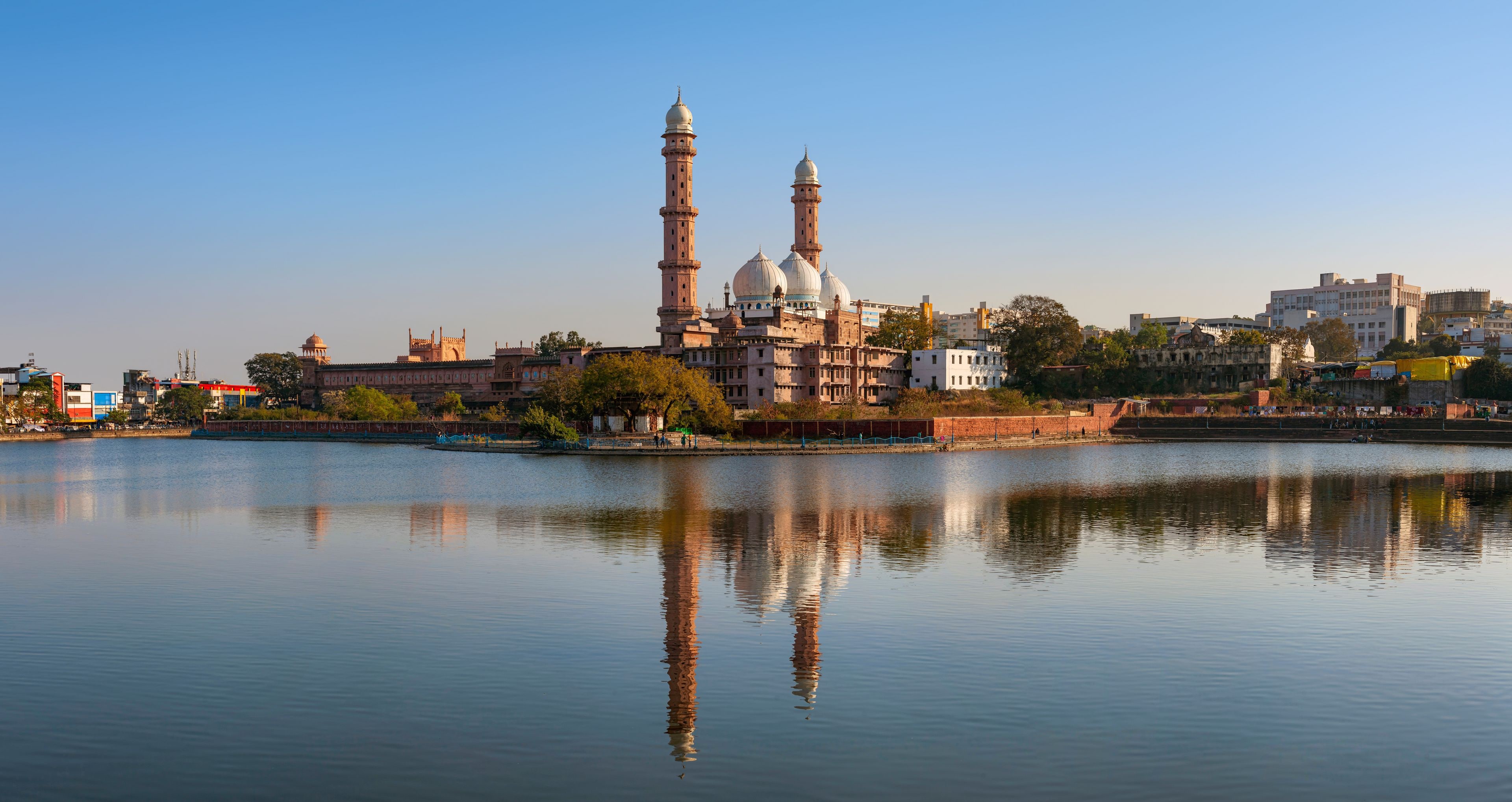 En historisk byggnad med kupoler och minareter som ligger vid en stilla flod.