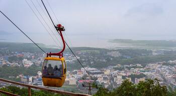 Eine Seilbahn mit Fahrgästen, einer Stadtlandschaft und einem Fluss im Hintergrund.