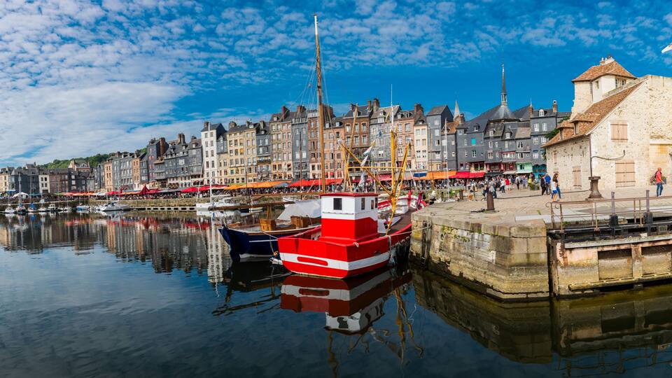 A harbor with boats, a red and white boat docked, and historic buildings along the waterfront.