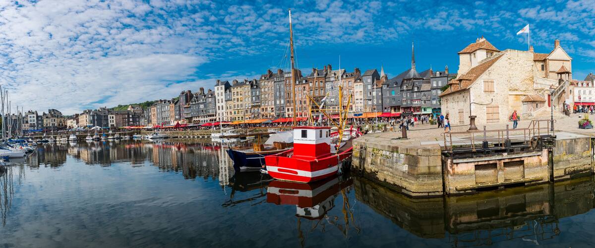 A harbor with boats, a red and white boat docked, and historic buildings along the waterfront.