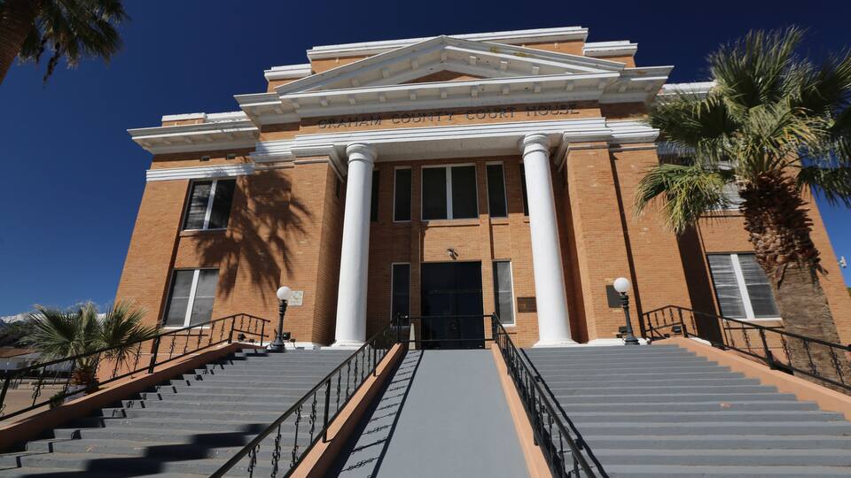 A courthouse with a grand entrance, large columns, and a staircase leading up to the door.
