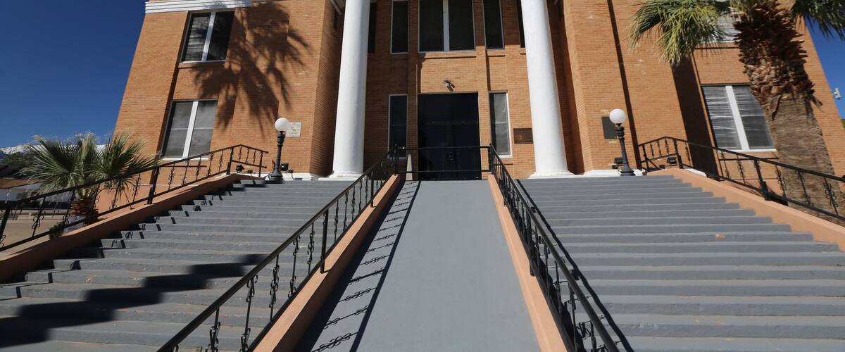 A courthouse with a grand entrance, large columns, and a staircase leading up to the door.
