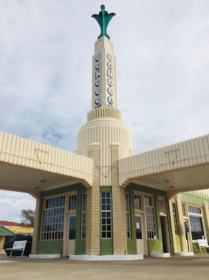 A vintage gas station with a distinctive tower and green awnings.