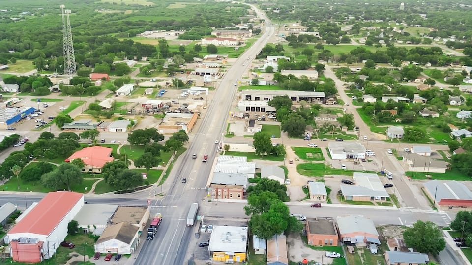 Panorama aerial view small town Three Rivers South of San Antonio along U.S. Highway 281, Texas, mix of industrial, business buildings and residential houses farmland, suburban rural, lush green