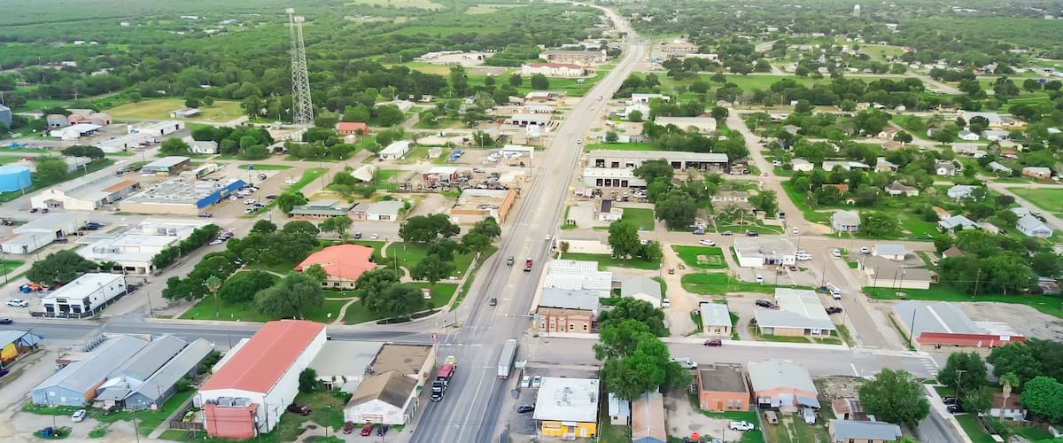 Panorama aerial view small town Three Rivers South of San Antonio along U.S. Highway 281, Texas, mix of industrial, business buildings and residential houses farmland, suburban rural, lush green