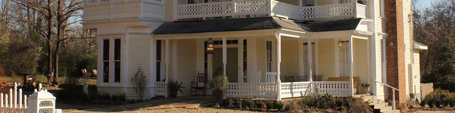 A large, white, two-story house with a black roof and multiple windows.