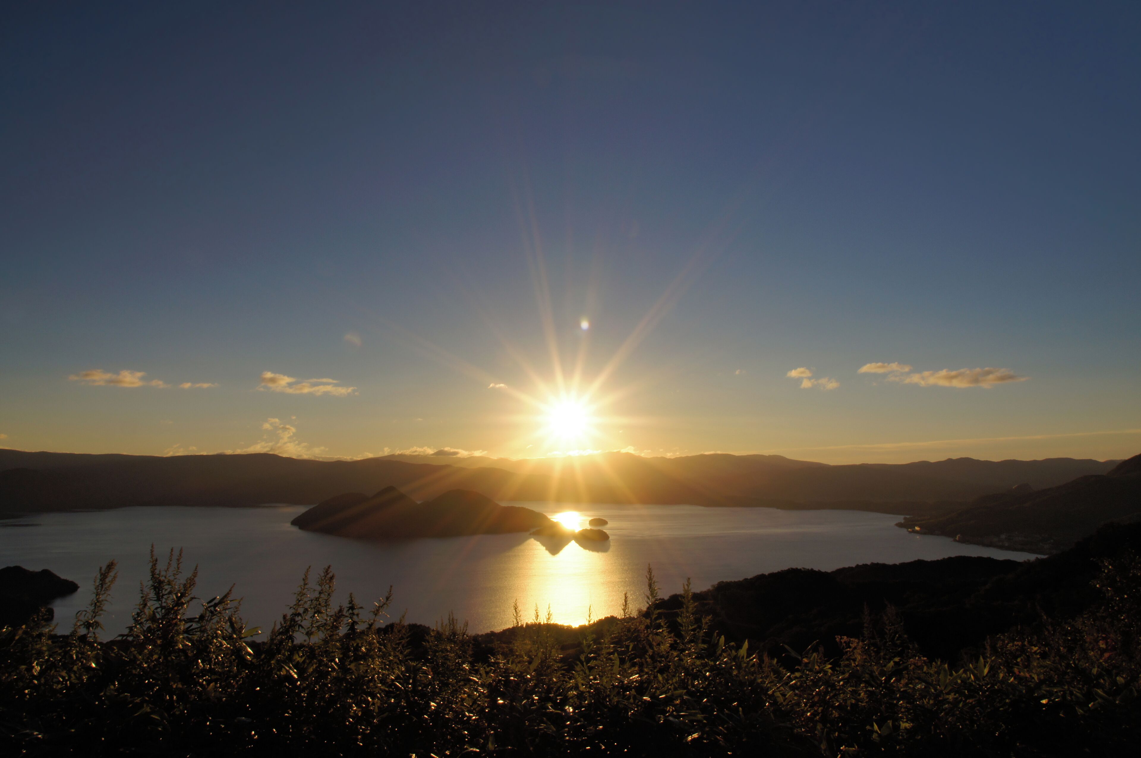 A sunset over a lake with mountains in the background.