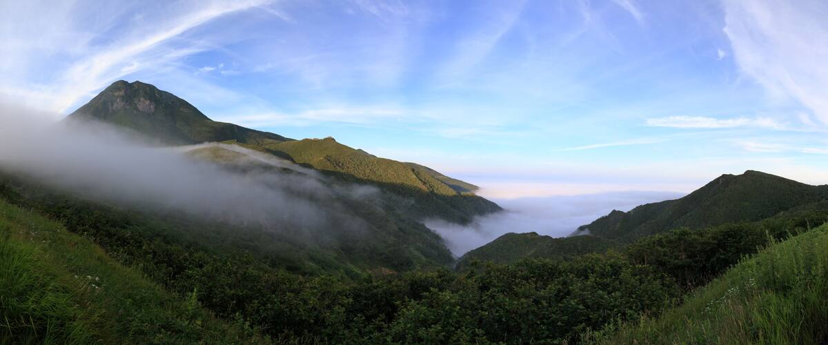 A mountain range with a prominent peak partially obscured by clouds.