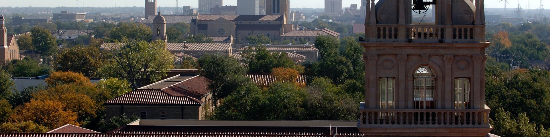 A historic clock tower surrounded by traditional buildings and trees.