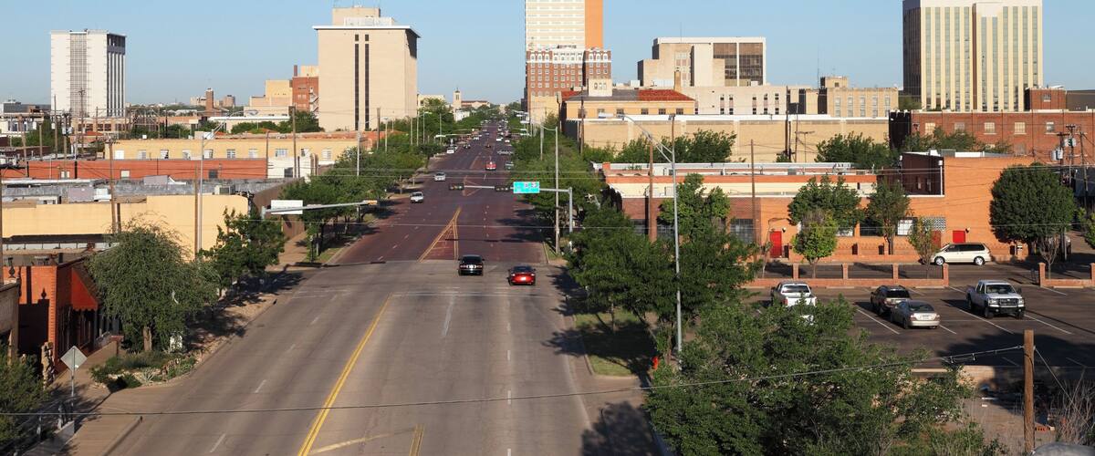 A city street with buildings, cars, and a clear sky.