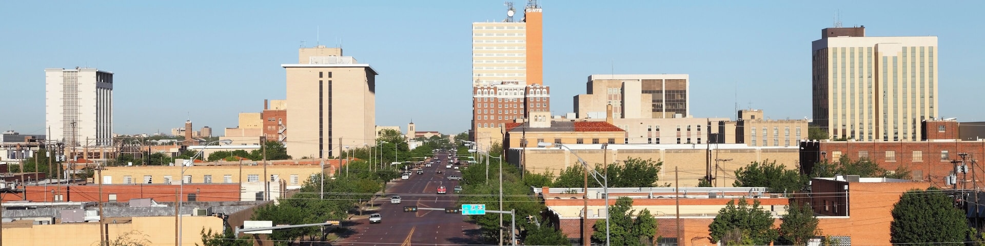 A city street with buildings, cars, and a clear sky.