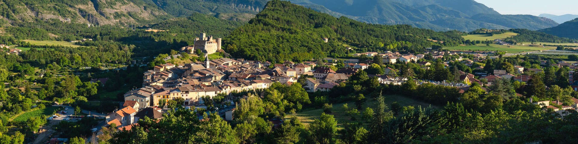 A town nestled in a valley surrounded by mountains, with a castle-like structure on a hill.