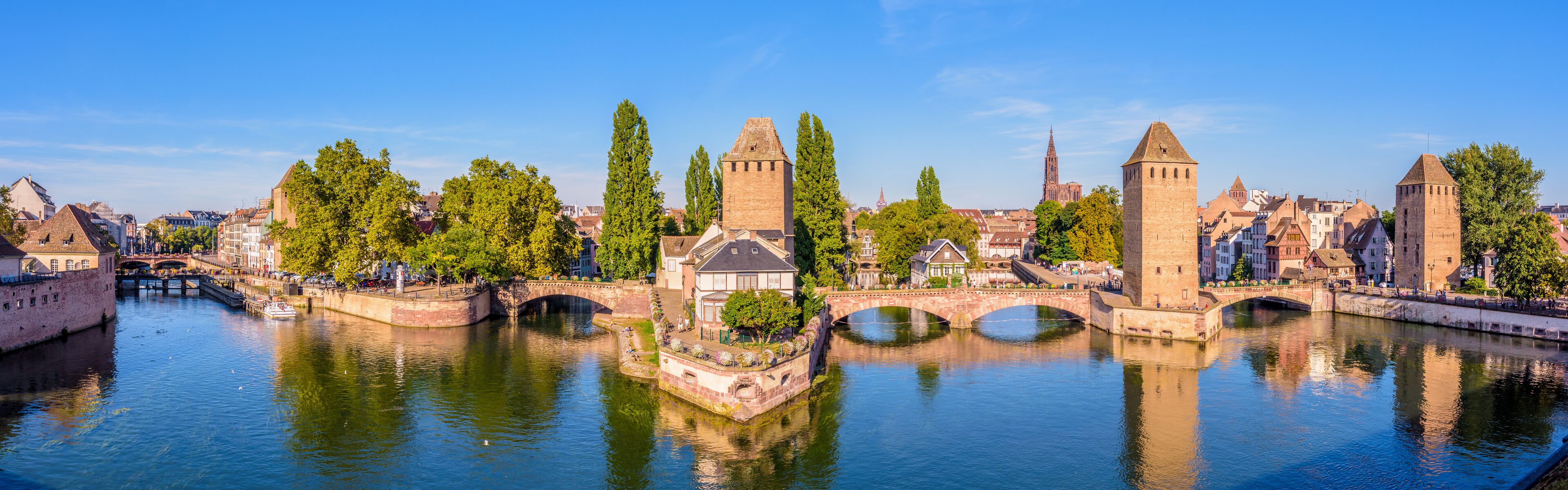 A historic cityscape with a river, bridges, and towers.