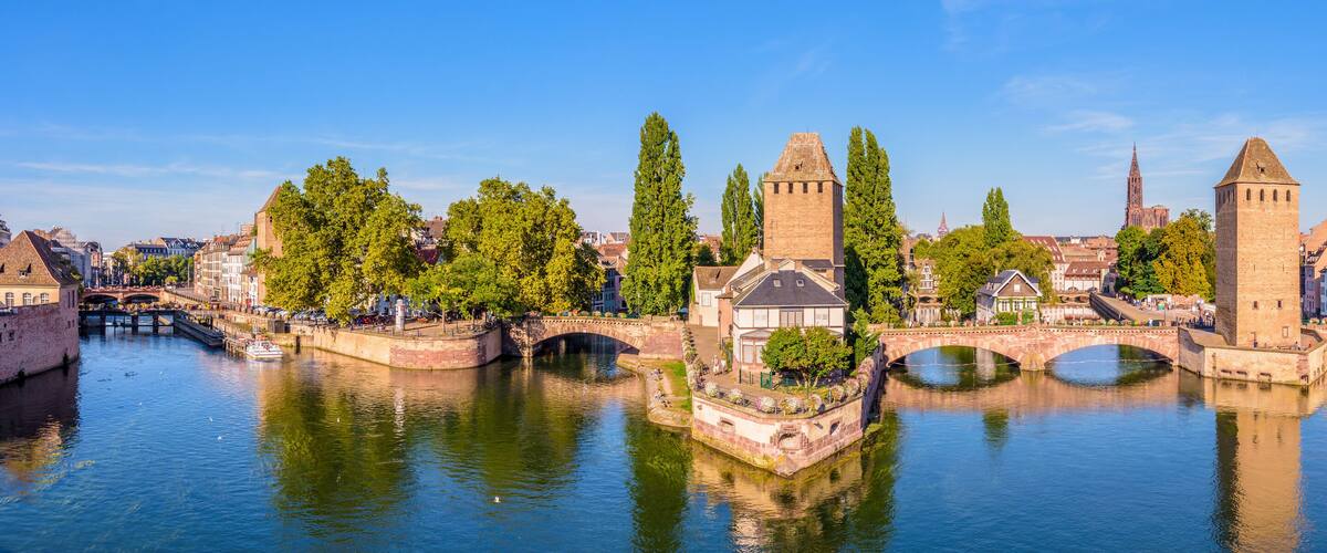 A historic cityscape with a river, bridges, and towers.