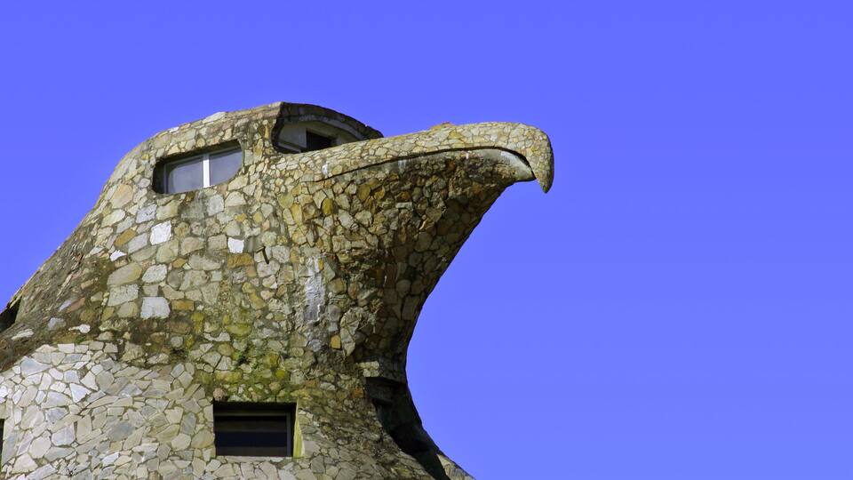 A building with a stone facade resembling a bird's head, featuring a beak and eye.