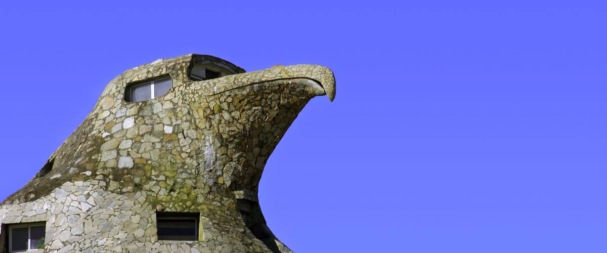 A building with a stone facade resembling a bird's head, featuring a beak and eye.