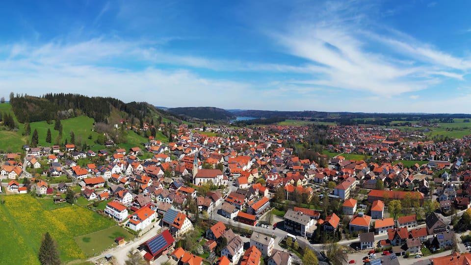 A town with red-roofed houses, green fields, and a church.