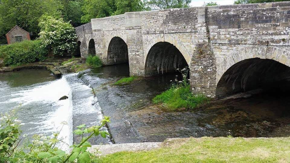 A stone bridge with three arches over a river.