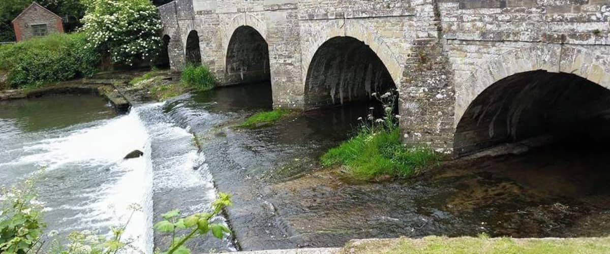 A stone bridge with three arches over a river.