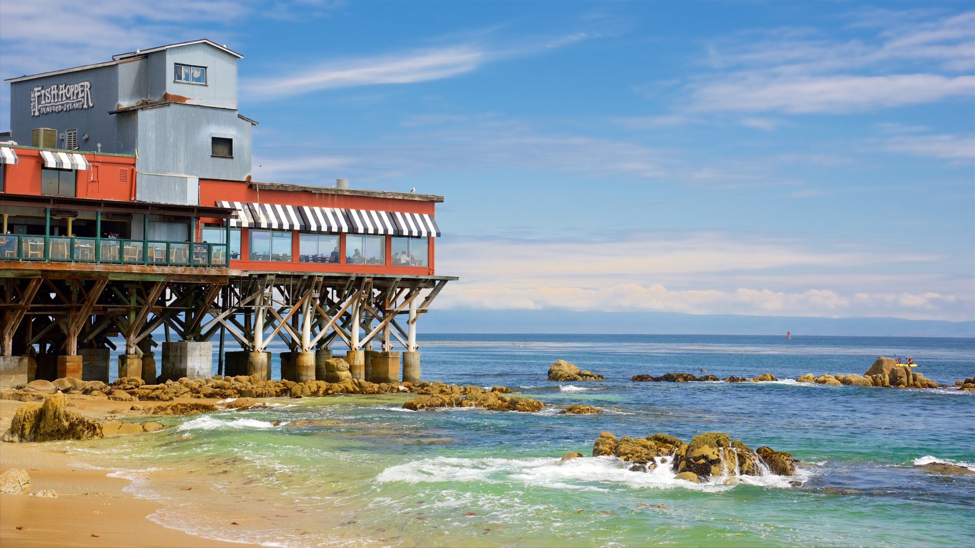 A coastal restaurant named Fish Hopper Seafood Steaks on stilts over the ocean.