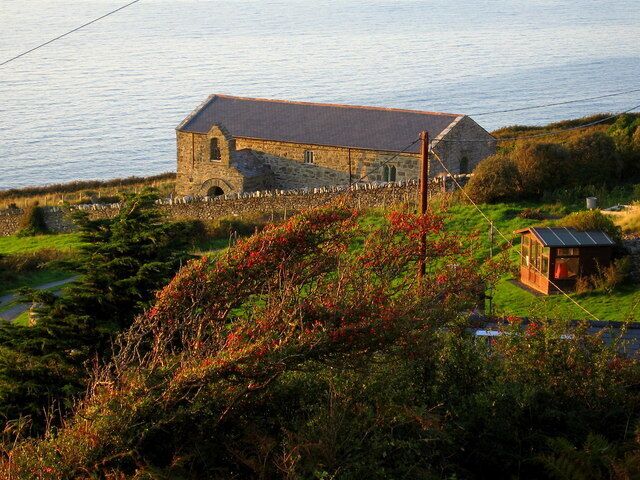 A stone building with a sloped roof near a body of water.