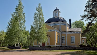 A yellow building with a dome and a tower, surrounded by trees.