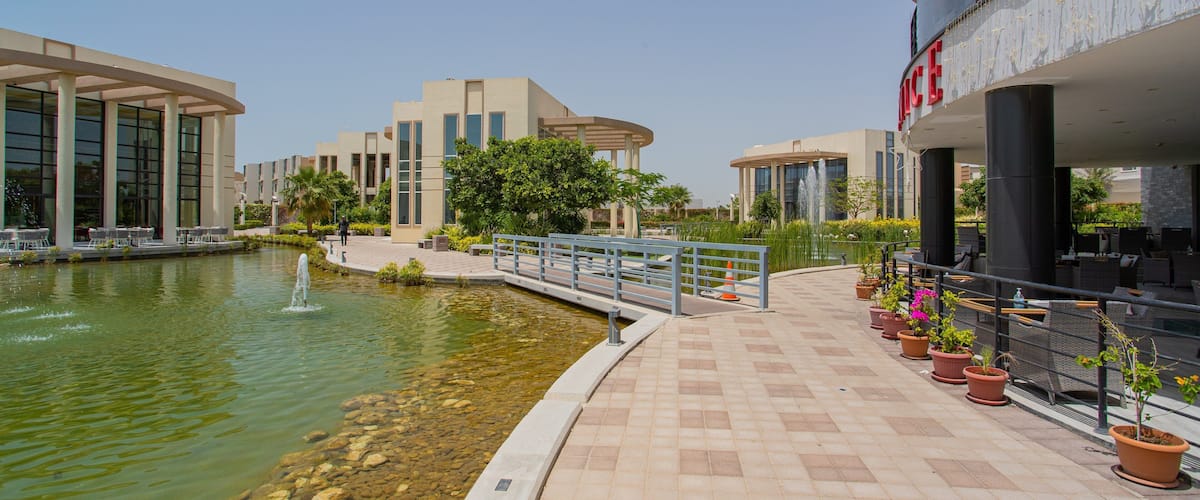 A modern building with a fountain, potted plants, and outdoor seating.