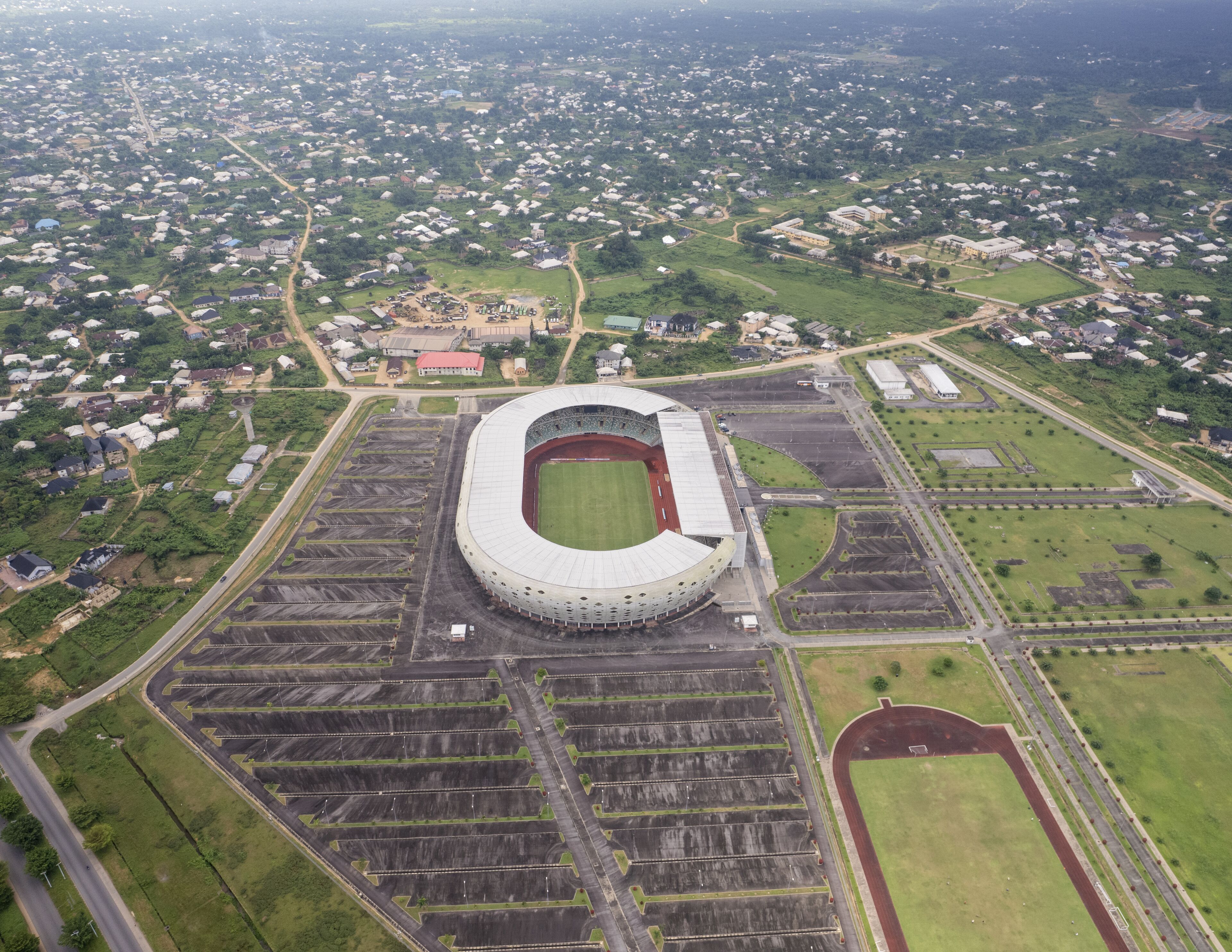 An aerial view of a stadium surrounded by residential areas and green fields.