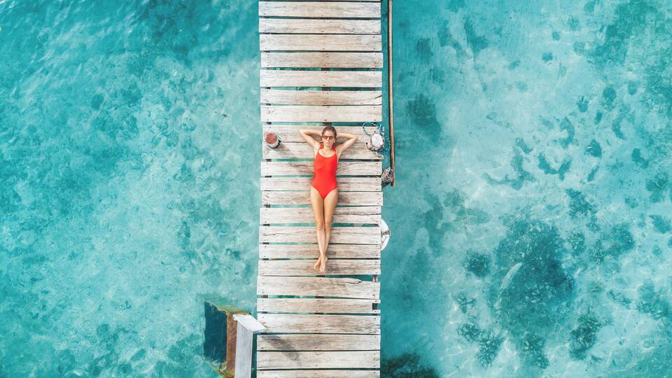 Aerial shot of womann relaxing in a water bungalow