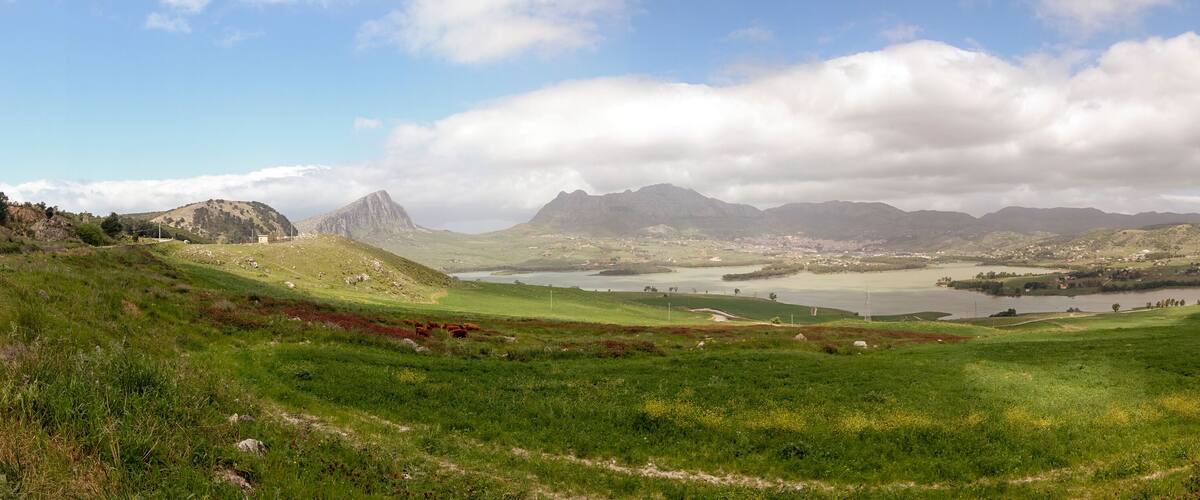 A mountainous landscape with a lake, a small town, and a prominent peak.