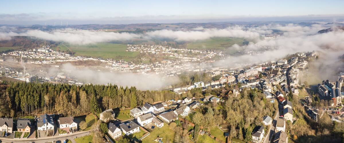 A town nestled in a valley with a forested hillside and a view of the surrounding landscape.