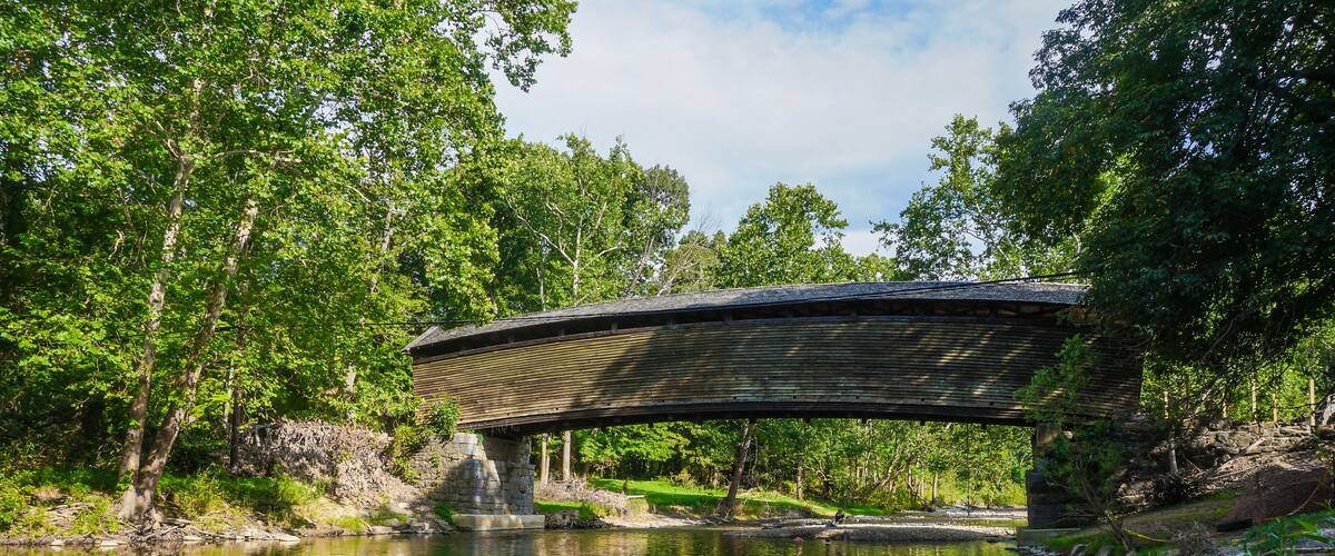 A wooden bridge over a calm river surrounded by lush greenery.