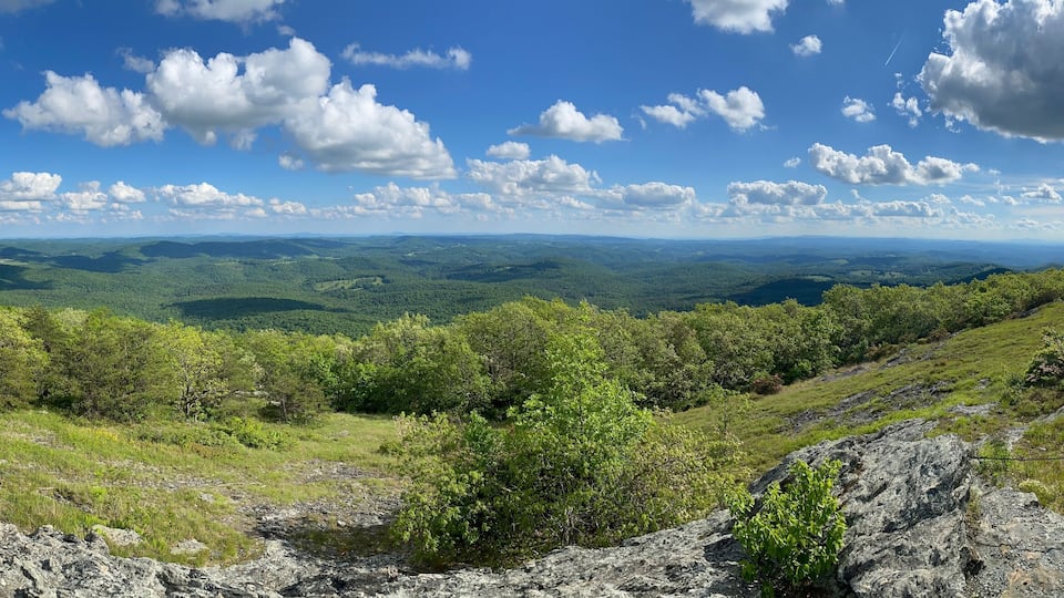 A mountainous landscape with a clear sky and scattered clouds.
