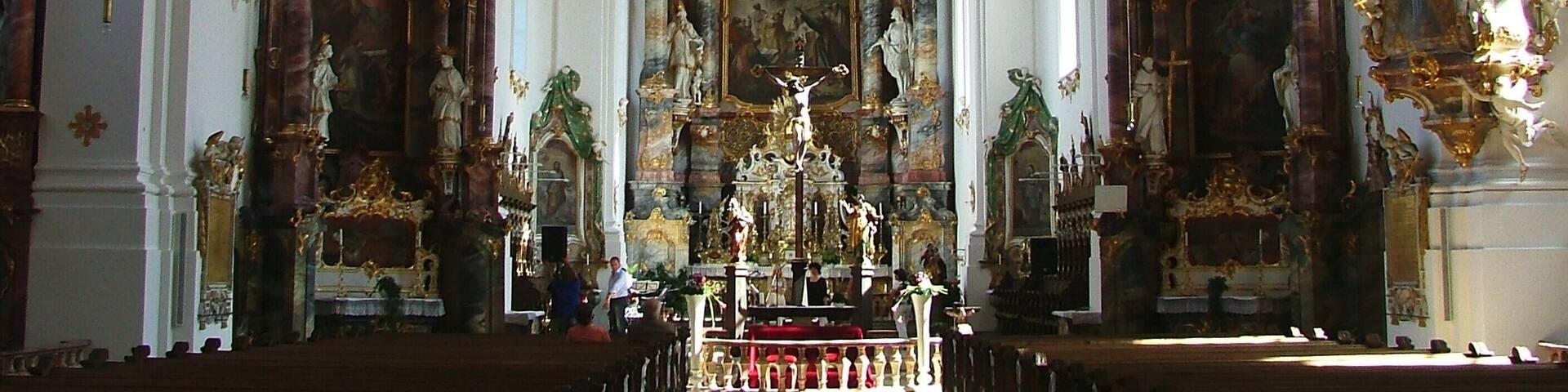 An ornate church interior with high ceilings, elaborate decorations, and a central altar.