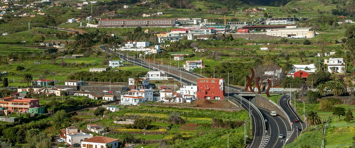 A mountainous landscape with a winding road, a train station, and scattered buildings.