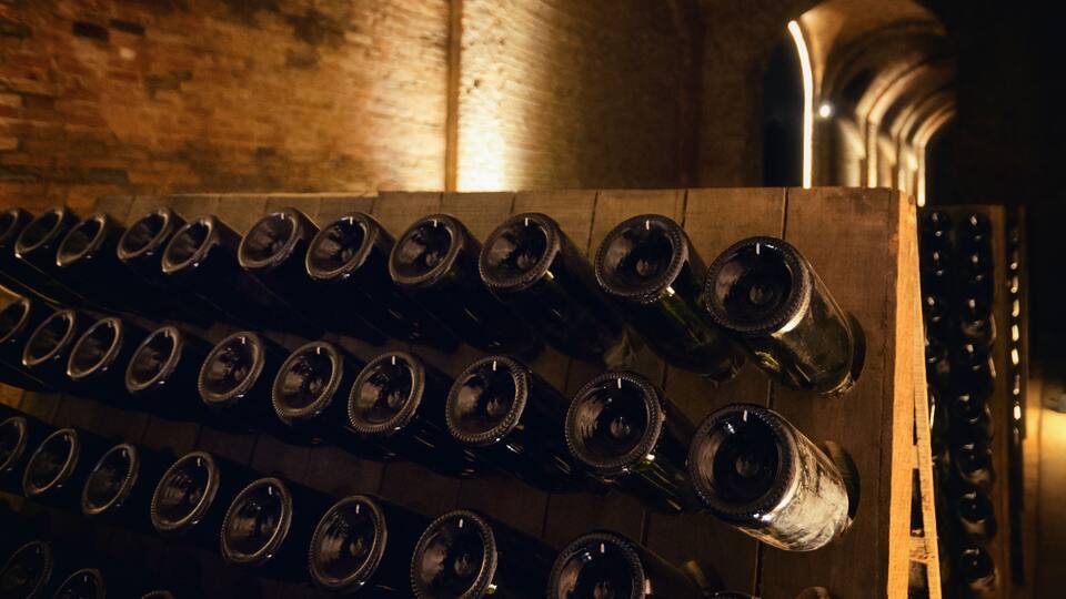 A wooden rack with multiple wine bottles.