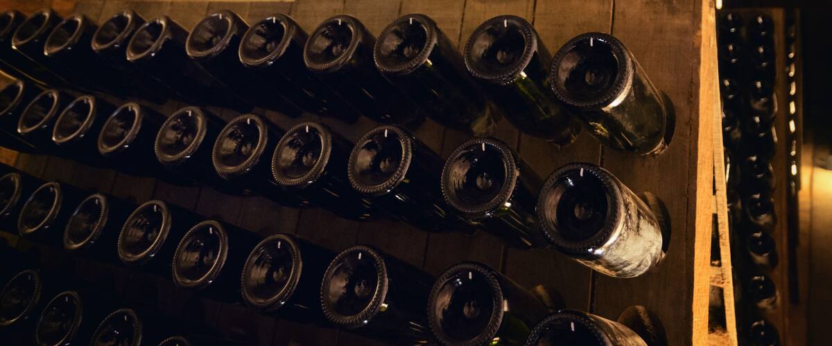 A wooden rack with multiple wine bottles.
