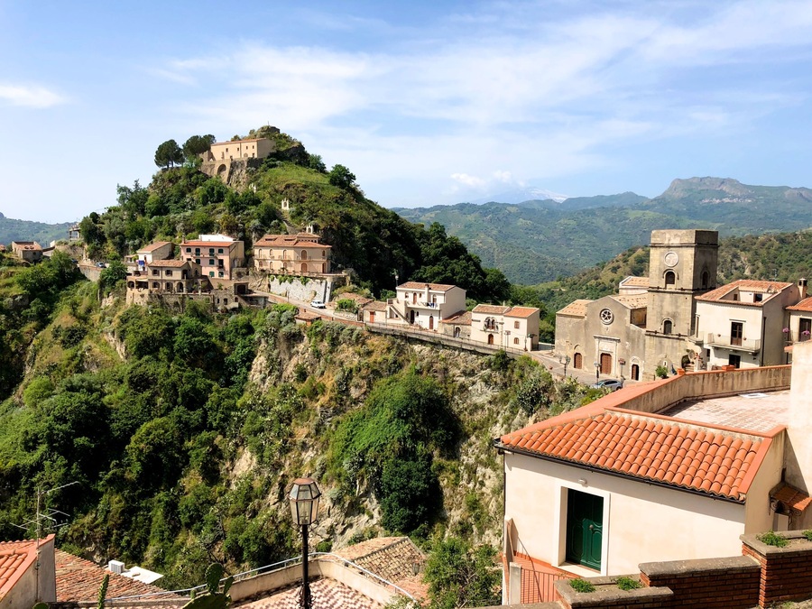 Savoca, one of the most beautiful villages in Italy, whose name is derived from the plant of the elder (savucu in Sicilian dialect), a shrub that still grows wild in the cracks between houses and which is represented in the medieval coat of arms of the village.
This small town set in the rock of a hill of dual tip, experienced the interest of kings, popes and Archimandrite prelates, in a succession of periods of serious crisis and prosperity. The basalt blocks lying on roads leading between separate small houses, freshly restored with Sicilian tiles on the roofs and windows framed in stone, then following streets in the rock here you’ll find extremely fragmented ruins and old cisterns.