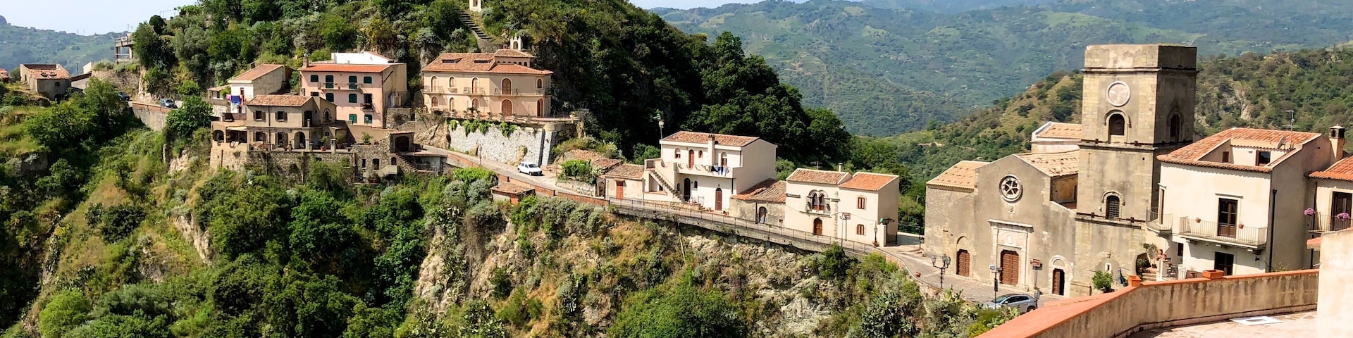 Savoca, one of the most beautiful villages in Italy, whose name is derived from the plant of the elder (savucu in Sicilian dialect), a shrub that still grows wild in the cracks between houses and which is represented in the medieval coat of arms of the village.
This small town set in the rock of a hill of dual tip, experienced the interest of kings, popes and Archimandrite prelates, in a succession of periods of serious crisis and prosperity. The basalt blocks lying on roads leading between separate small houses, freshly restored with Sicilian tiles on the roofs and windows framed in stone, then following streets in the rock here you’ll find extremely fragmented ruins and old cisterns.