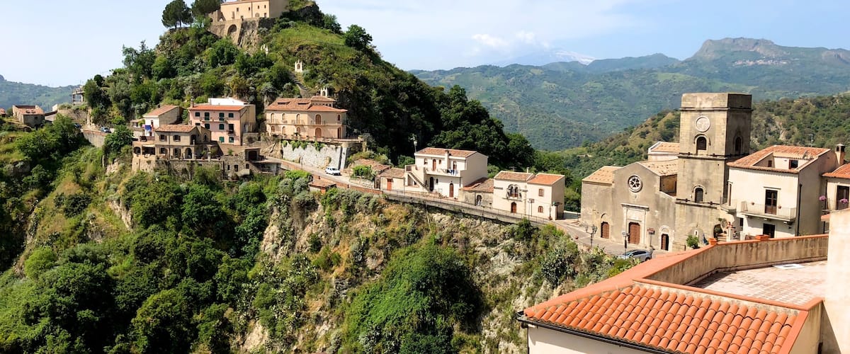 A hillside village with terraced houses, a church, and a castle on a hill.