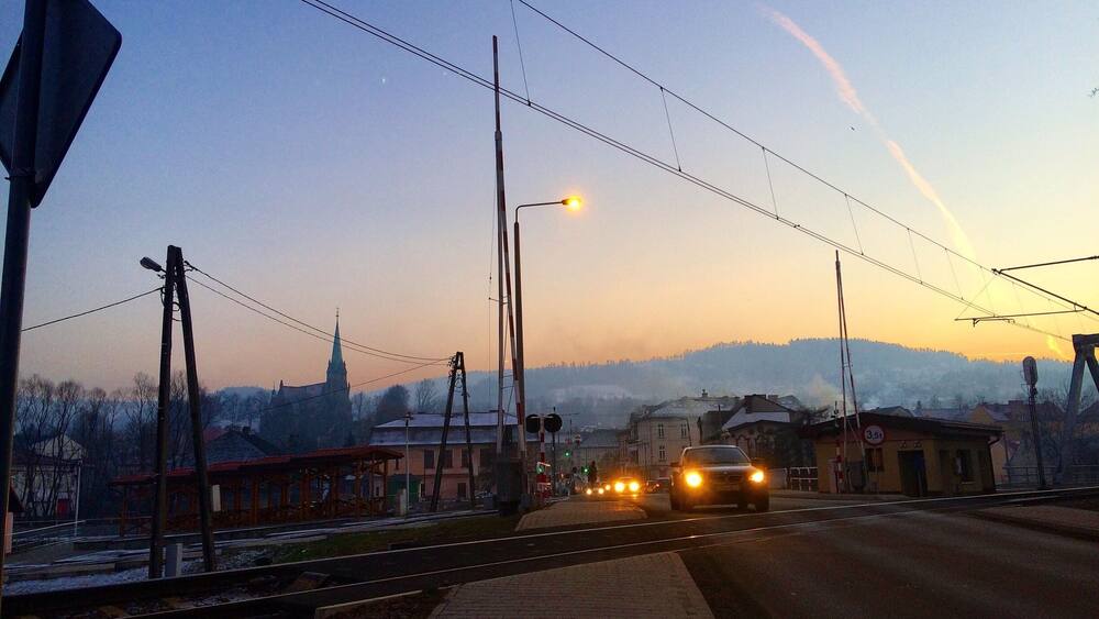 A road with cars, streetlights, and a church in the background.