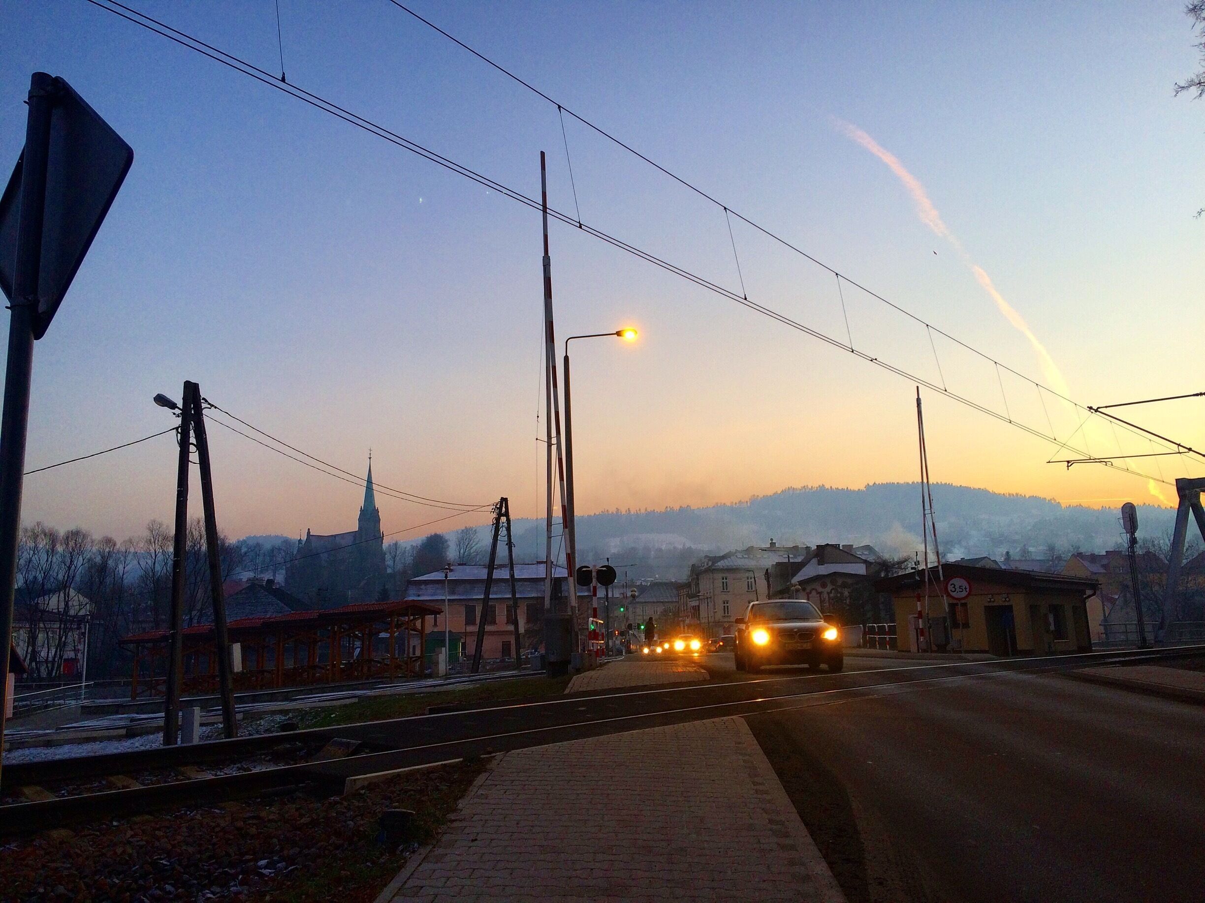 A road with cars, streetlights, and a church in the background.