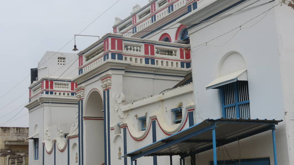 A row of white buildings with red and blue trim and decorative arches.