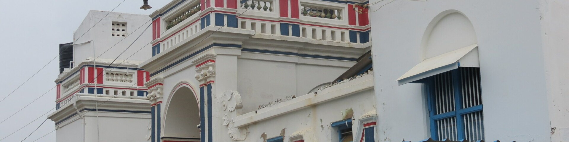 Uma fileira de edifícios brancos com detalhes em vermelho e azul e arcos decorativos.