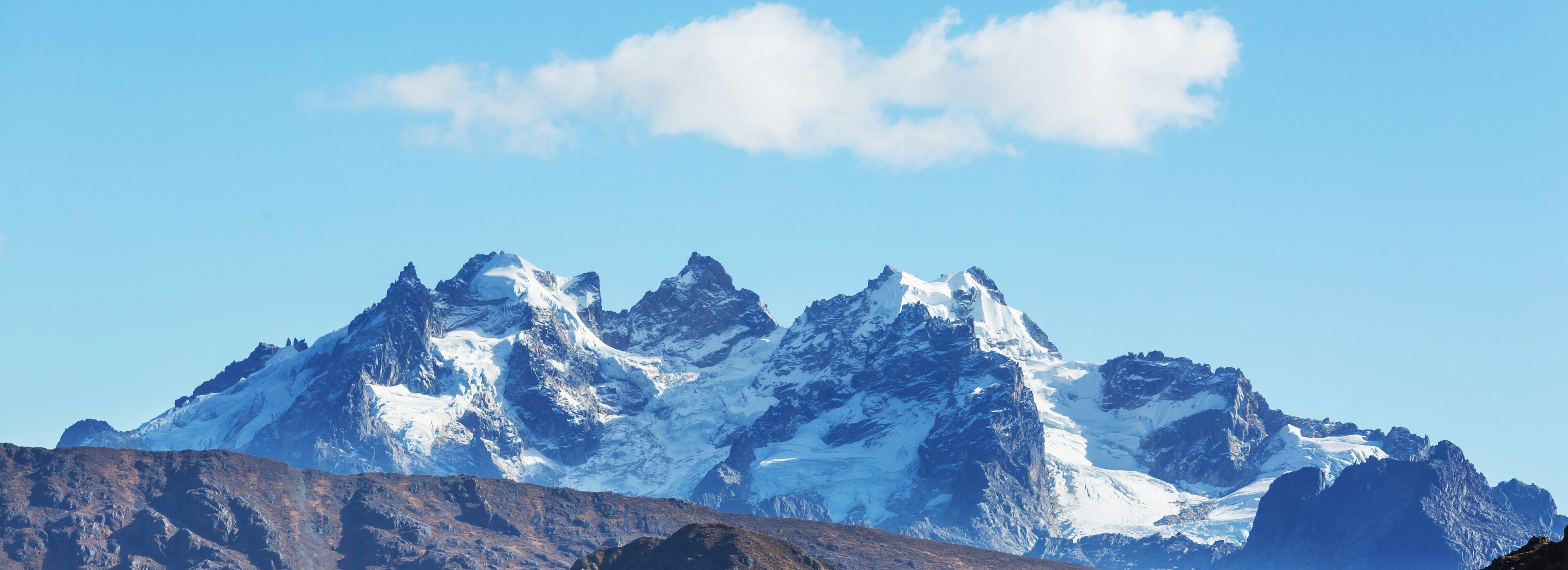 A snow-capped mountain range with rugged peaks under a clear blue sky.