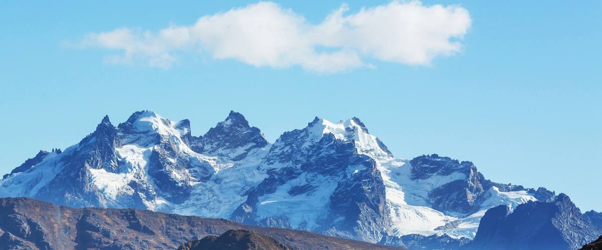 A snow-capped mountain range with rugged peaks under a clear blue sky.