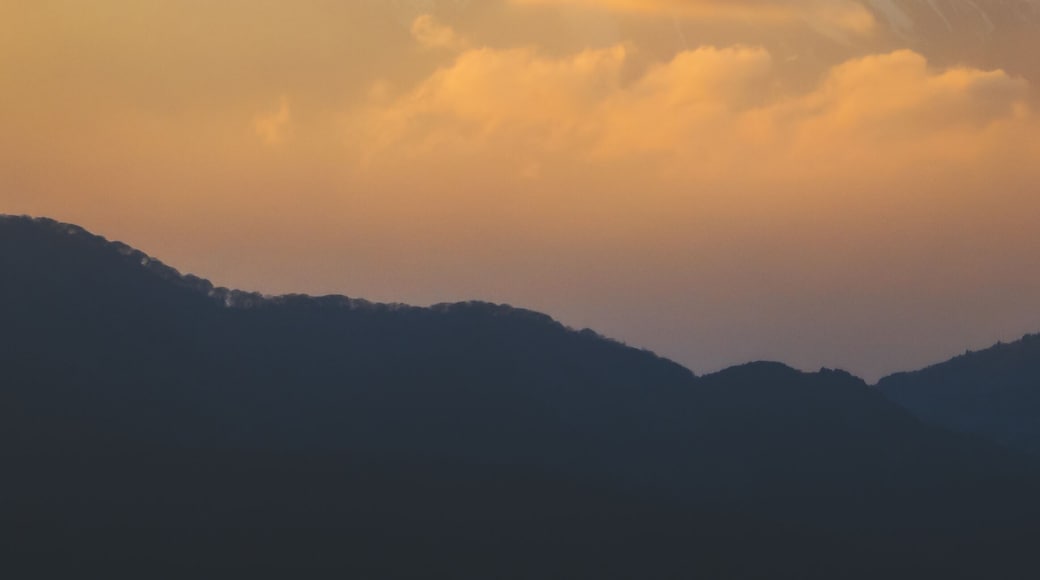 Aerial view of Mount Fuji's snow-capped peak piercing through golden clouds at sunset, a majestic sight from afar, Mt. Taikan Observation Deck, Kanagawa, Japan.