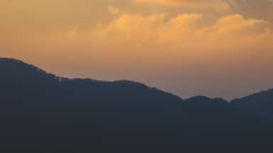 Aerial view of Mount Fuji's snow-capped peak piercing through golden clouds at sunset, a majestic sight from afar, Mt. Taikan Observation Deck, Kanagawa, Japan.